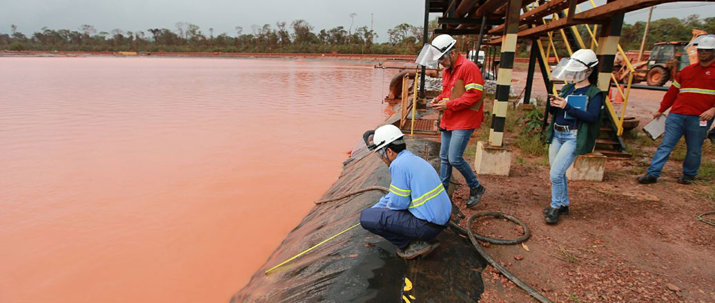 people inspecting a red mud deposit