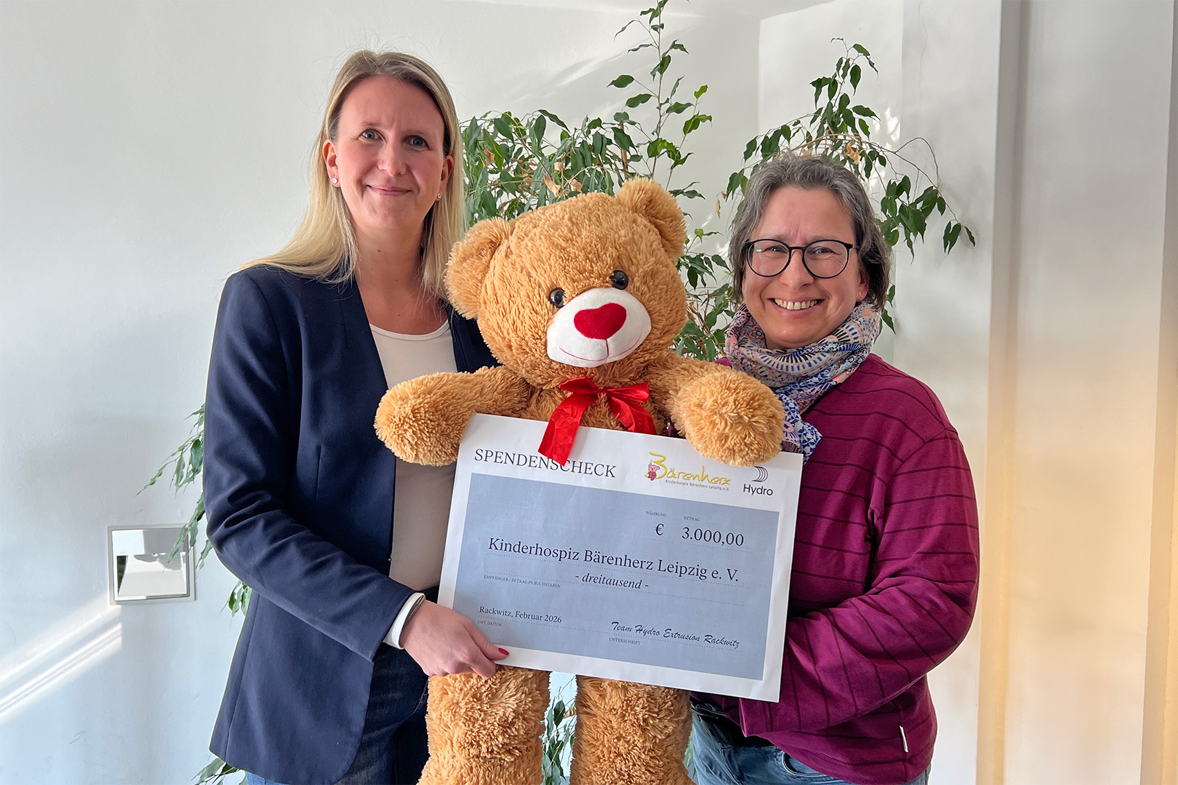 two women holding a large teddy bear