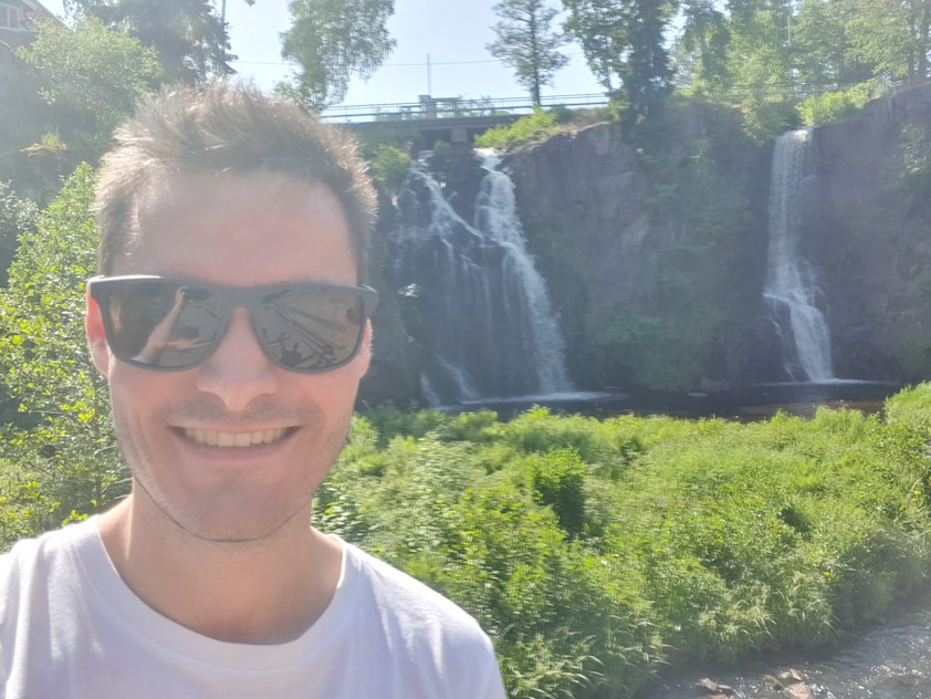 a man taking a selfie in front of a waterfall
